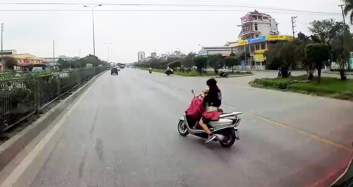 Video: Cô gái vừa cởi áo mưa, vừa ôm em bé chạy xe